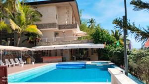 a villa with a swimming pool in front of a house at SunSea Resort in Guimaras