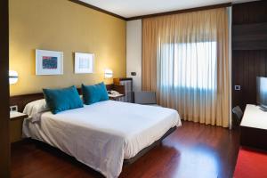 a hotel room with a large bed with blue pillows at Hotel America Igualada in Igualada