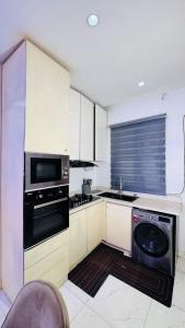 a kitchen with white cabinets and a dishwasher at The Jimi Stay in Maiyegun +7 photos