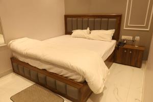 a bed with a wooden frame and white sheets and pillows at Aachman Restaurent in Bulandshahr