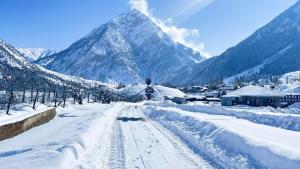 a road covered in snow with mountains in the background at Gurez knights in Kanzalwan