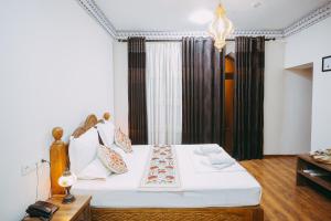 a bedroom with a bed with white sheets and pillows at Royal Bukhara hotel in Bukhara