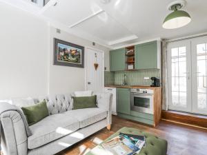 a living room with a couch and a kitchen at Firefly Cottage in Cirencester