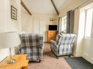 a living room with two chairs and a television at Mews Cottage 5 in Keswick