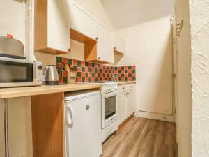 a small kitchen with white cabinets and a microwave at Mews Cottage 5 in Keswick +4 photos