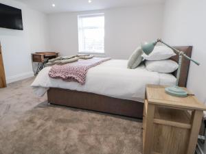 a bedroom with a bed with a lamp and a table at 10 South Street in Rossendale
