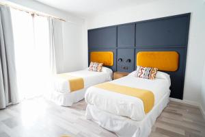 two beds in a room with white and yellow at Hotel La Chiquita in Córdoba