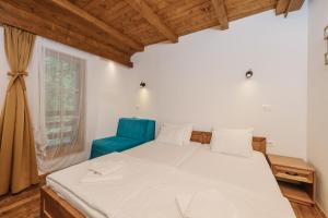 a bedroom with a bed and a blue chair at Hotel Porto Tara in Žabljak