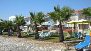 a resort with palm trees and chairs and umbrellas at Seafront Escape Apartment in Oroklini