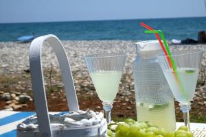 a table with two drinks and a basket of grapes at Seafront Escape Apartment in Oroklini +22 photos