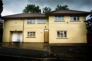 a large yellow house with two garage at Spacious House Sleeps 10 -Near BikePark Wales -Central -Parking in Troed-y-rhiw
