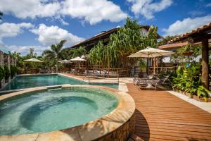 a swimming pool with a wooden deck next to a house at Pousada Carcará - JERI in Jericoacoara