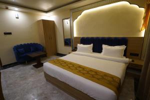 ein Hotelzimmer mit einem großen Bett und einem blauen Stuhl in der Unterkunft PS Marriott Hotel in Patna