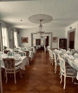 a dining room with white tables and chairs and a chandelier at Munkedals Herrgård in Munkedal