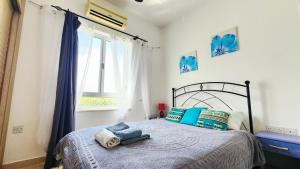 a bedroom with a bed with blue pillows and a window at Apartament Palm Bay View Esentepe Bahceli in Kyrenia +27 photos