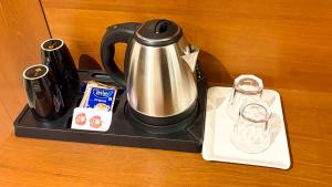 a tea kettle on a black tray with a coffee maker at Hotel Sterling Executive in Navi Mumbai
