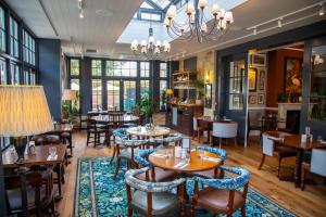 a restaurant with tables and chairs and a chandelier at The Chalk Hare, Royston, Hertfordshire - Acorn Pubs in Royston