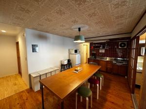 a kitchen with a large wooden table and chairs at Aburatsu Inn Kadocco in Nichinan