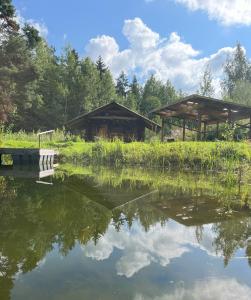 a pond with two gazebos in the background at Glämping Jantsu talus in Pilka