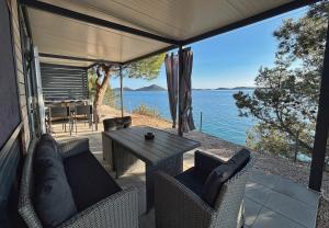 a patio with a table and chairs and a view of the water at Hipo camp - Mobil home Sestrica in Pakoštane