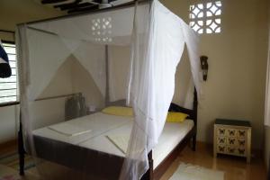 a bed with a canopy in a room at Villa Madinina in Diani Beach
