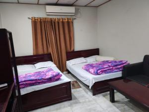 a bedroom with two beds and a table at Hotel Mohsin Plaza in Sreemangal