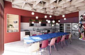 a kitchen with a long blue table and pink chairs at MEININGER Hotel Edinburgh Haymarket in Edinburgh