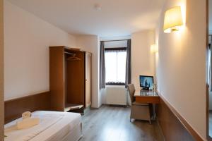 a bedroom with a bed and a desk with a computer at Hotel Baeren in Leimen