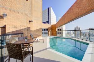 a balcony with a table and chairs and a swimming pool at Hampton Park São Paulo Jardins in São Paulo