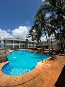 a swimming pool with palm trees in front of a building at Villa das Araras Residence in Porto Seguro