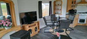 a living room with a dining table and a television at Stacaravan in De Pol
