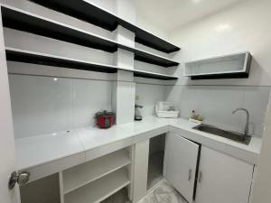 a white kitchen with white counters and a sink at Pinkys Guest House in Allen