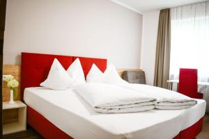 a bedroom with a red and white bed with white pillows at Pension Tannenhof in Laces