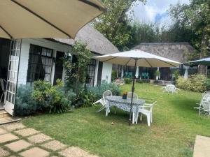 a table and chairs with an umbrella in a yard at Muco Guest House in Johannesburg