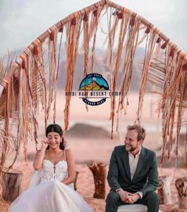 a bride and groom sitting under a tent on the beach at WADl RUM DESERT CAMP in Wadi Rum