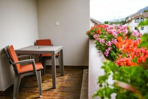 a table and chairs in a balcony with flowers at Pension Tannenhof in Laces