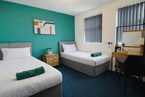 a hotel room with two beds and a desk at Royal Chambers Liverpool in Liverpool