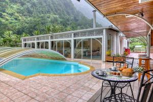 a house with a swimming pool with a table and a patio at L'Escale Royale in Salazie