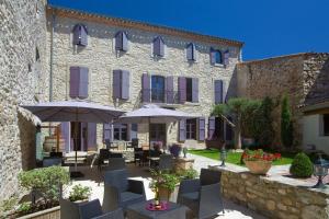 a building with chairs and umbrellas in front of it at Bed & Breakfast Demeure du Pareur in Villeneuve-Minervois