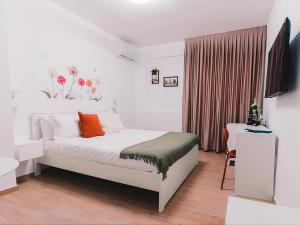 a white bedroom with a bed and a television at La tana del Furlo in Acqualagna