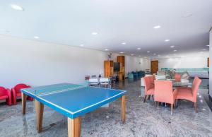 a ping pong table in a room with chairs at Hotel Aojesp in Caraguatatuba