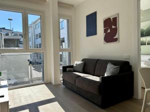 a living room with a black couch and some windows at Bressanone Apartments in Milan