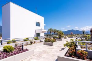 a white building with a bunch of plants on it at Hotel Aojesp in Caraguatatuba