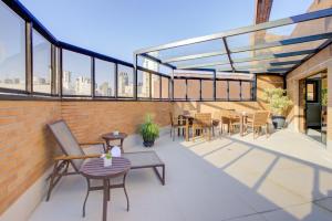 a balcony with chairs and tables and windows at Hampton Park São Paulo Jardins in São Paulo