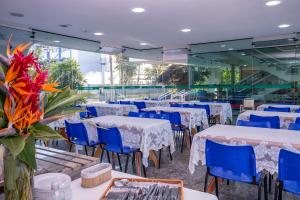 a banquet hall with tables and blue chairs at Hotel Aojesp in Caraguatatuba
