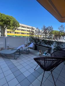 a patio with chairs and tables and a building at Hotel Del Corso in Bibione
