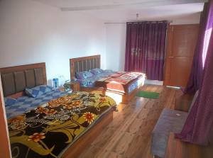 two beds in a room with wooden floors at The Devine homestay in Ukhimath