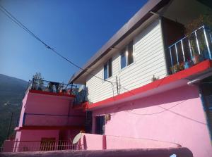 a pink and white building with people on the balcony at The Devine homestay in Ukhimath