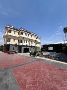 a large white building with benches in front of it at Enseno Hotel in Karshi