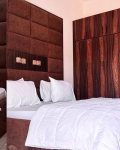 a bedroom with a white bed with a wooden headboard at Enseno Hotel in Karshi